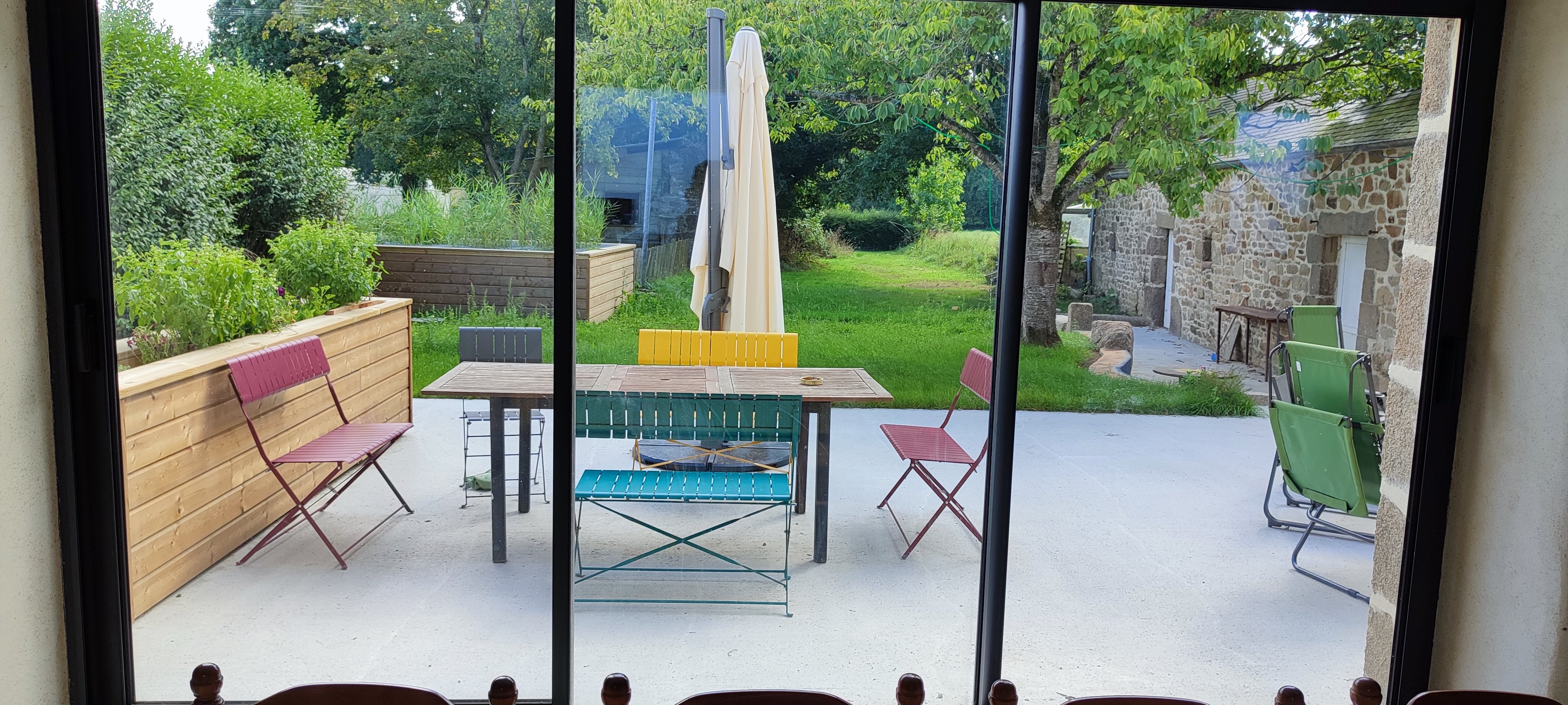 Terrasse conviviale de gîte breton avec vue sur le jardin paisible, l'endroit idéal pour se détendre et profiter de la nature